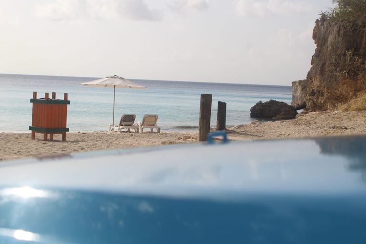 Infinity pool overlooking a tropical beach with lounge chairs and clear blue ocean.