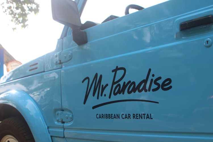 Bright blue jeep with 'Mr. Paradise Caribbean Car Rental' logo on the side.